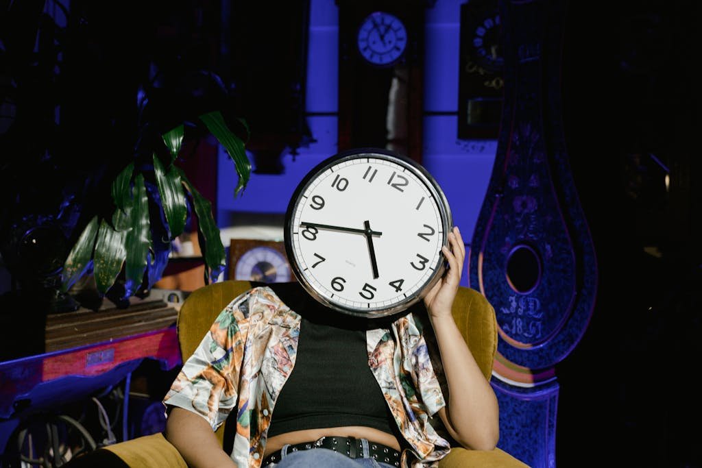 A person with a clock head sitting in a colorful room, creating a surreal atmosphere.